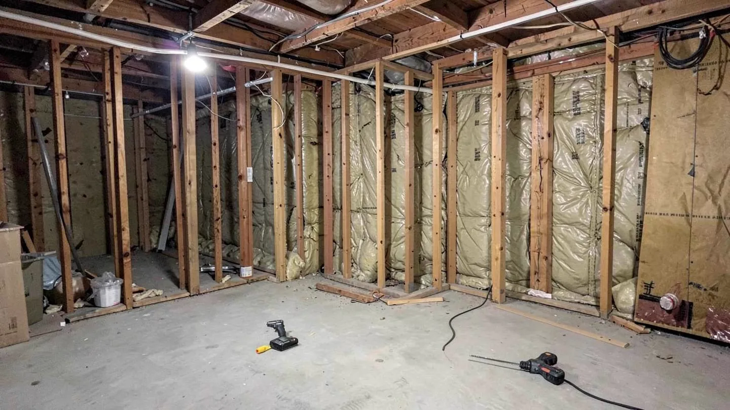 New stud framing and insulation going up along the walls of an unfinished basement