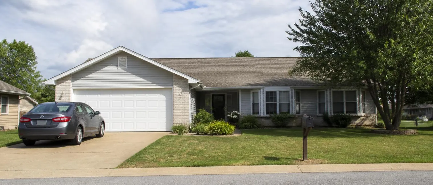 The front exterior of an ordinary suburban home with a car in the driveway