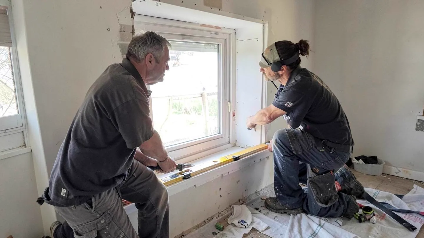 Two installers levelling a new replacement window in a prepared opening