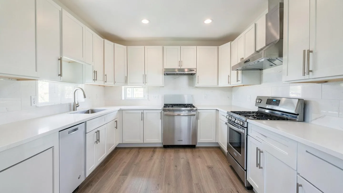 An updated kitchen with white shaker cabinets, quartz counters and a stainless range